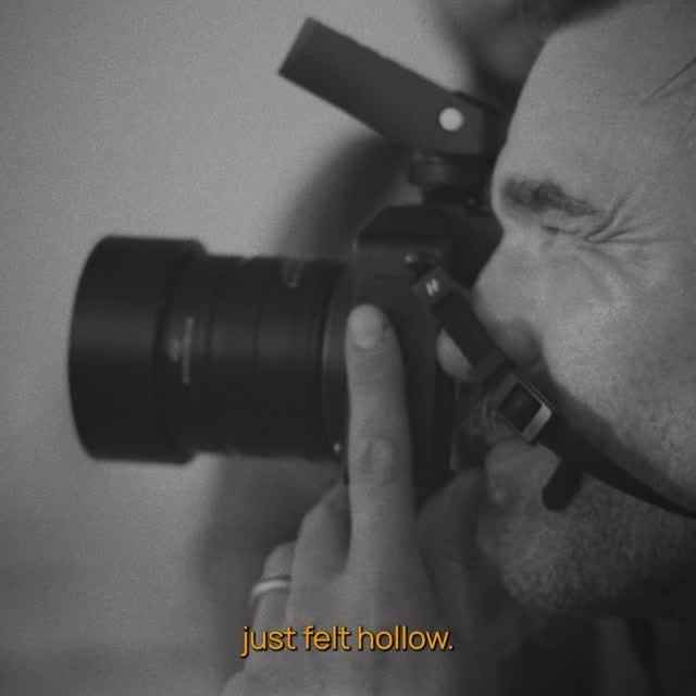 Black-and-white close-up of a photographer using a camera, with subtitle text reading “just felt hollow.”