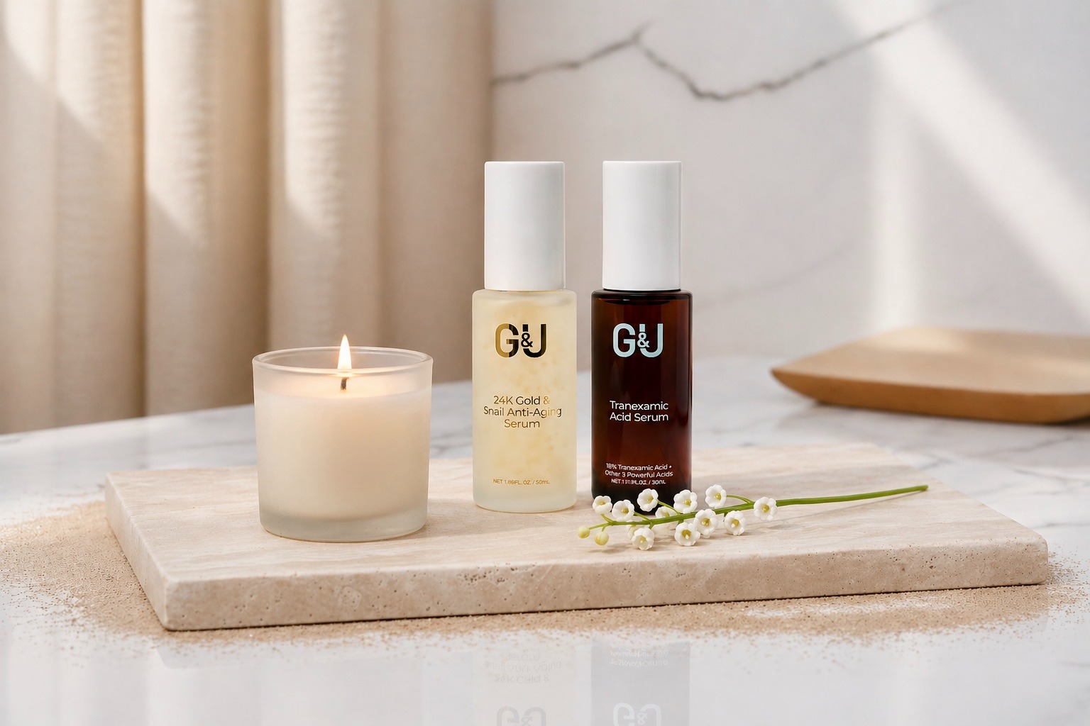 A lit candle, two skincare serum bottles, and white flowers sit on a marble tray. The soft lighting and neutral tones create a serene spa-like ambiance.