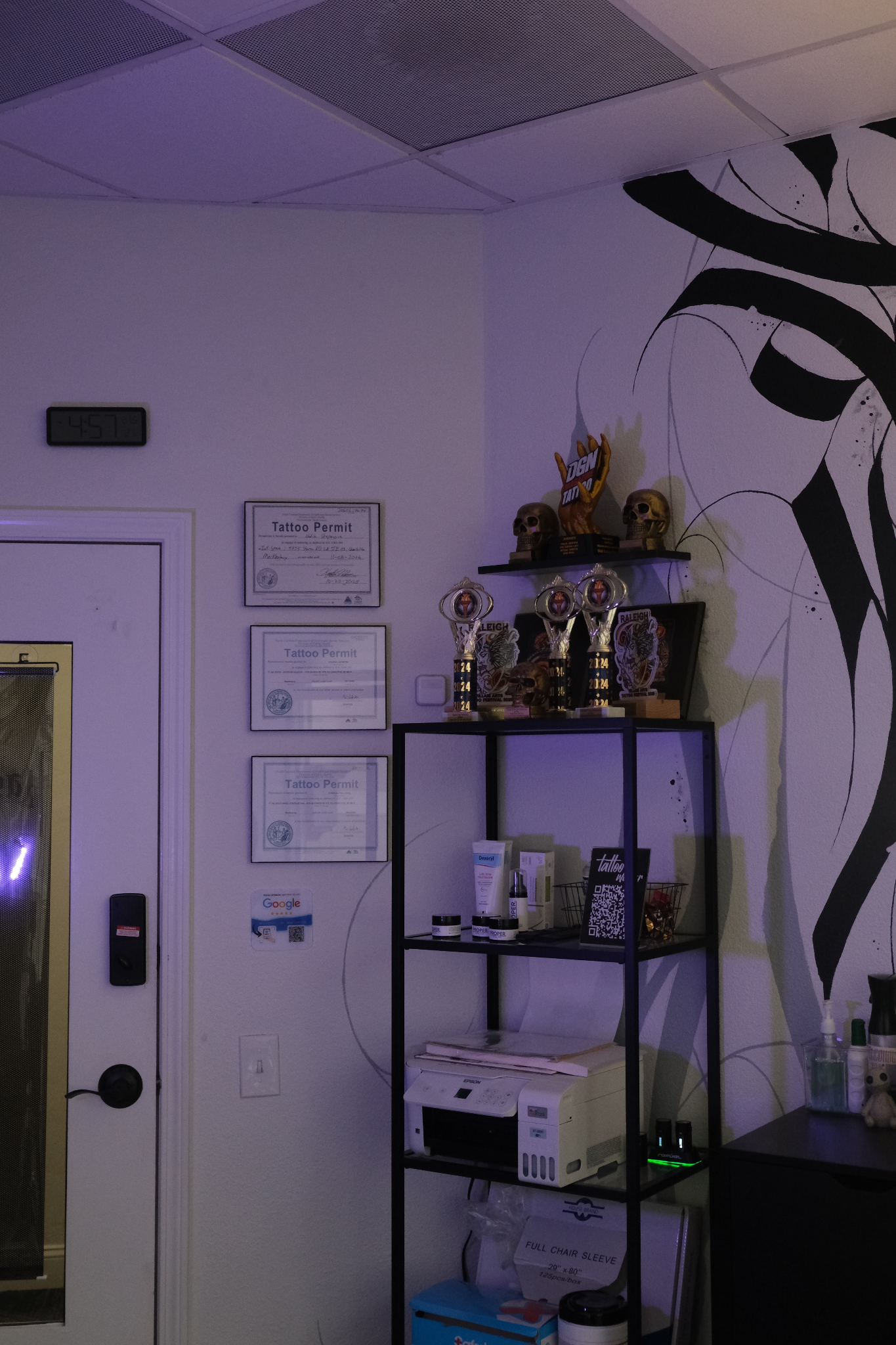 Tattoo studio interior with awards, permits, and modern decor display.