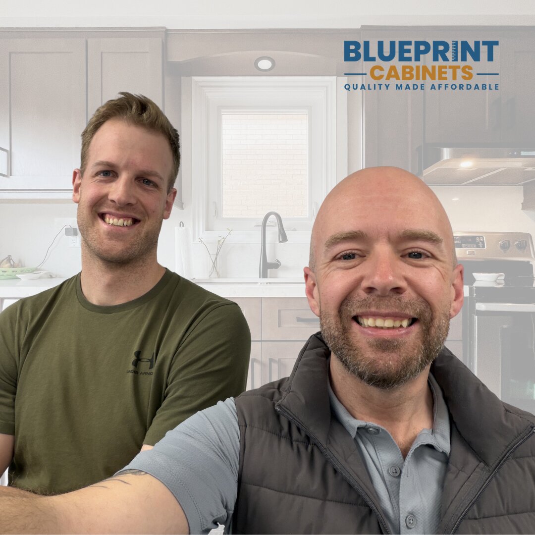 Two smiling men posing in kitchen showroom with Blueprint Cabinets logo in background.