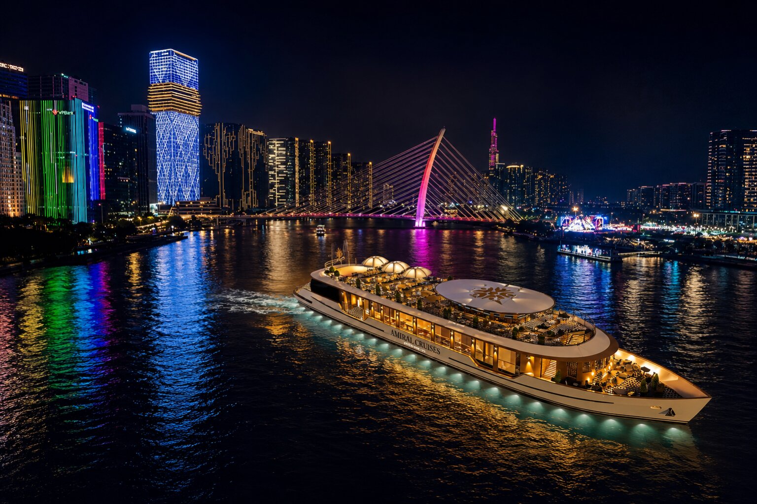 Luxury Amiral Cruises yacht sailing Saigon River at night beneath illuminated city skyline and bridge.