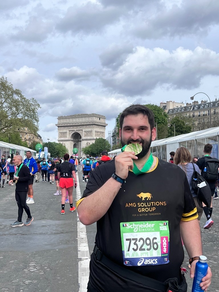 Marathon runner celebrates Paris Marathon finish near the Arc de Triomphe.
