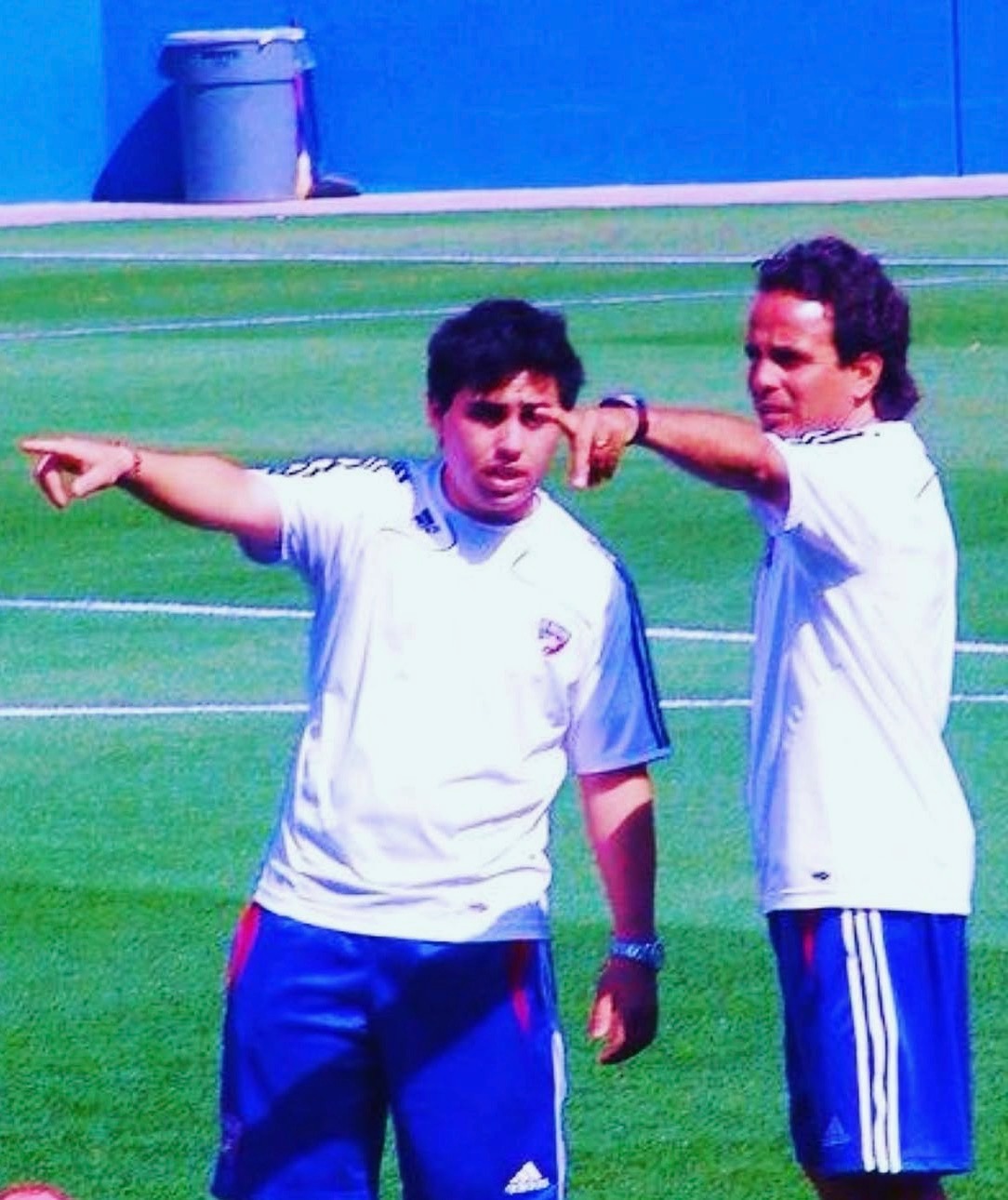 Two soccer coaches on field pointing and giving instructions during training