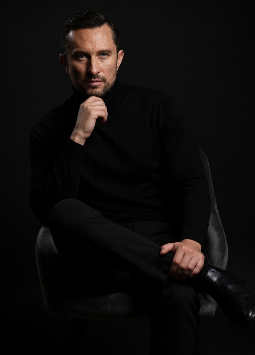 Portrait Image: Bart Radka, CEO of RADKA ADVERTISING, sitting in a chair, wearing black attire.