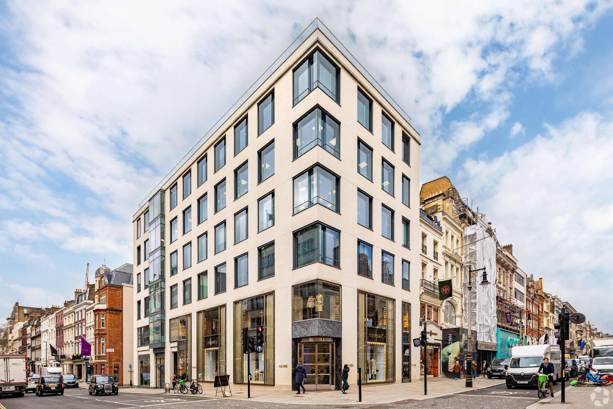 Modern corner building in London with large windows and luxury retail storefronts at street level.