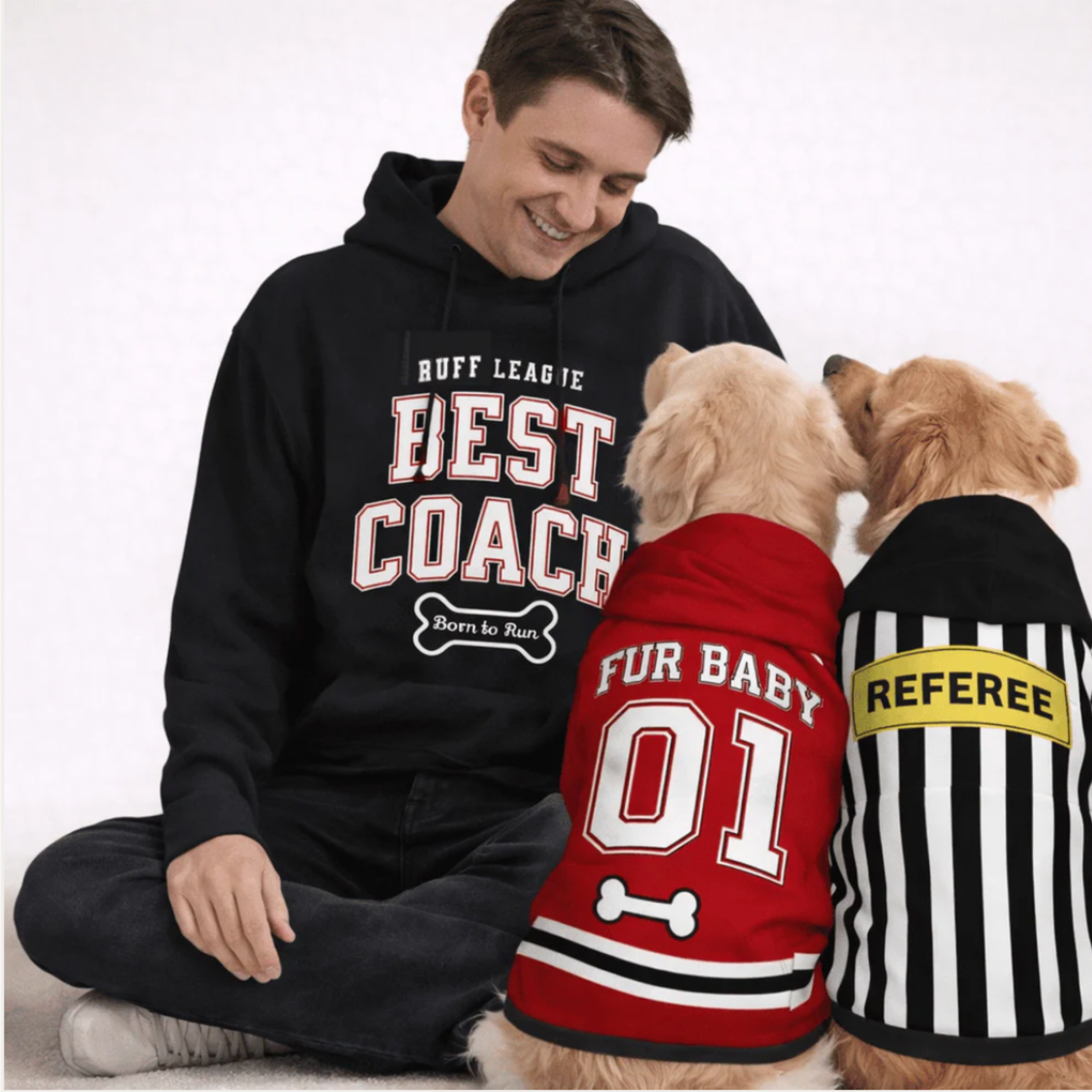 Man in “Best Coach” hoodie posing with two dogs in matching sports-inspired pet outfits.