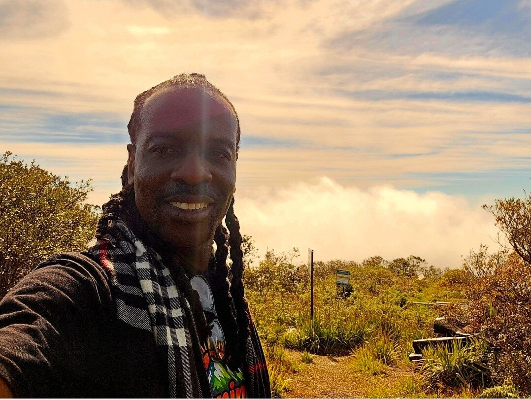 Author Cleous G. Young smiling in outdoor mountain setting and formal blue suit portrait.