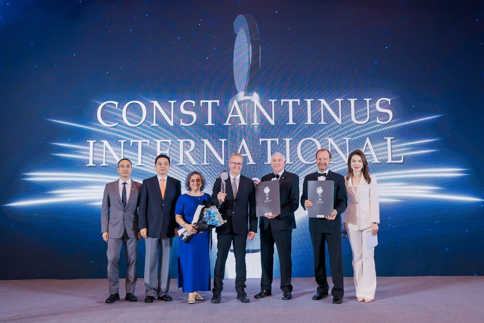 Group photo at Constantinus International awards, with consultants holding trophies and certificates on stage.
