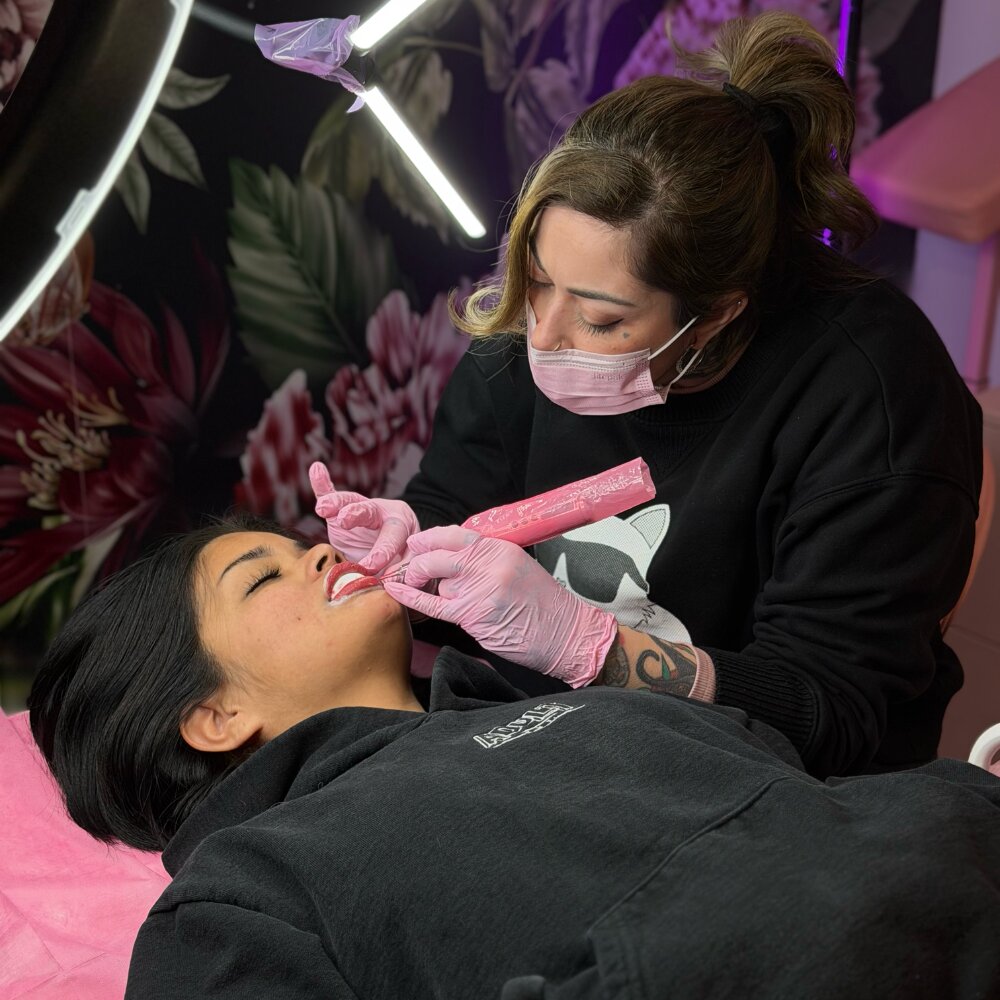 Permanent makeup artist applying lip blush treatment to client at The Iconic Parlour studio in 29 Palms.