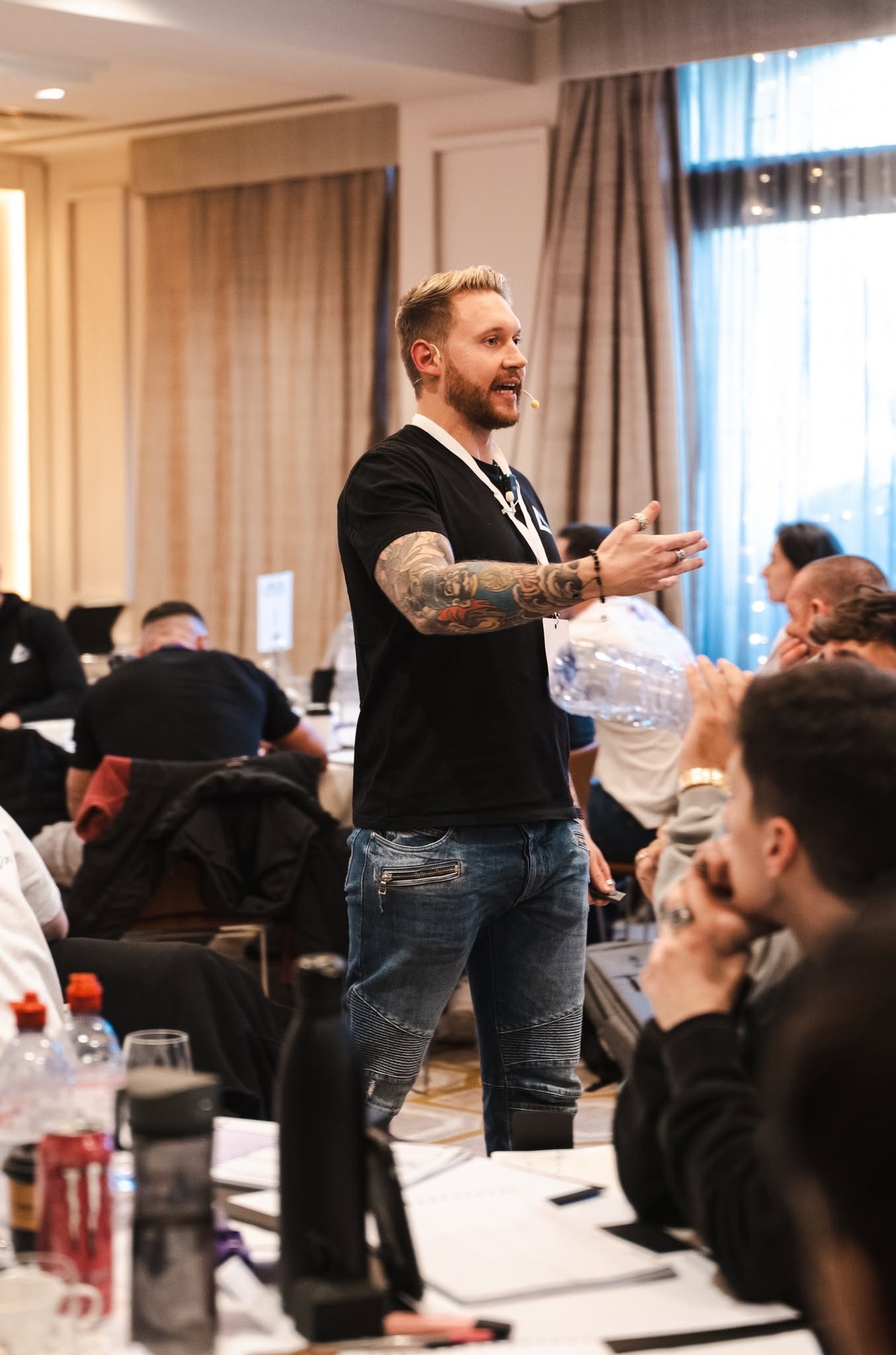 Stephen Cheevers leads an interactive business training session, speaking to attendees in a conference room.