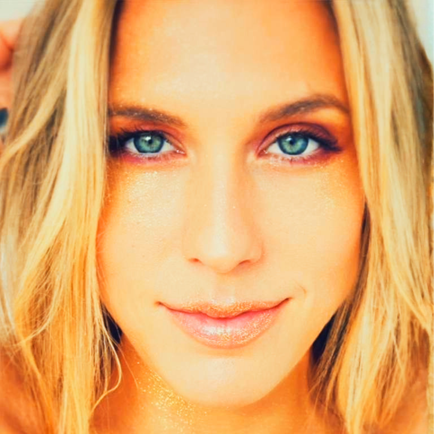 Close-up portrait of a blonde woman with blue eyes and subtle makeup.