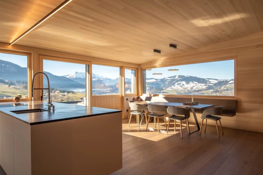 Luxury mountain home interior with panoramic windows overlooking snow-dusted Vail Valley peaks.