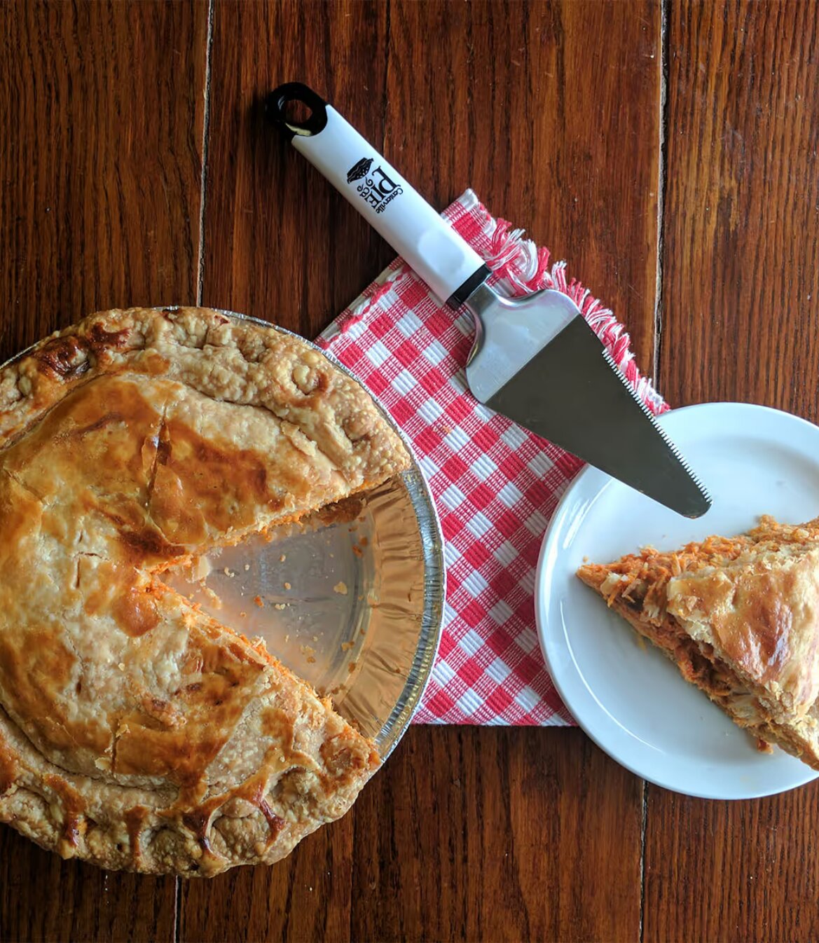 Freshly baked savory pie with a slice served on a plate beside a pie server.