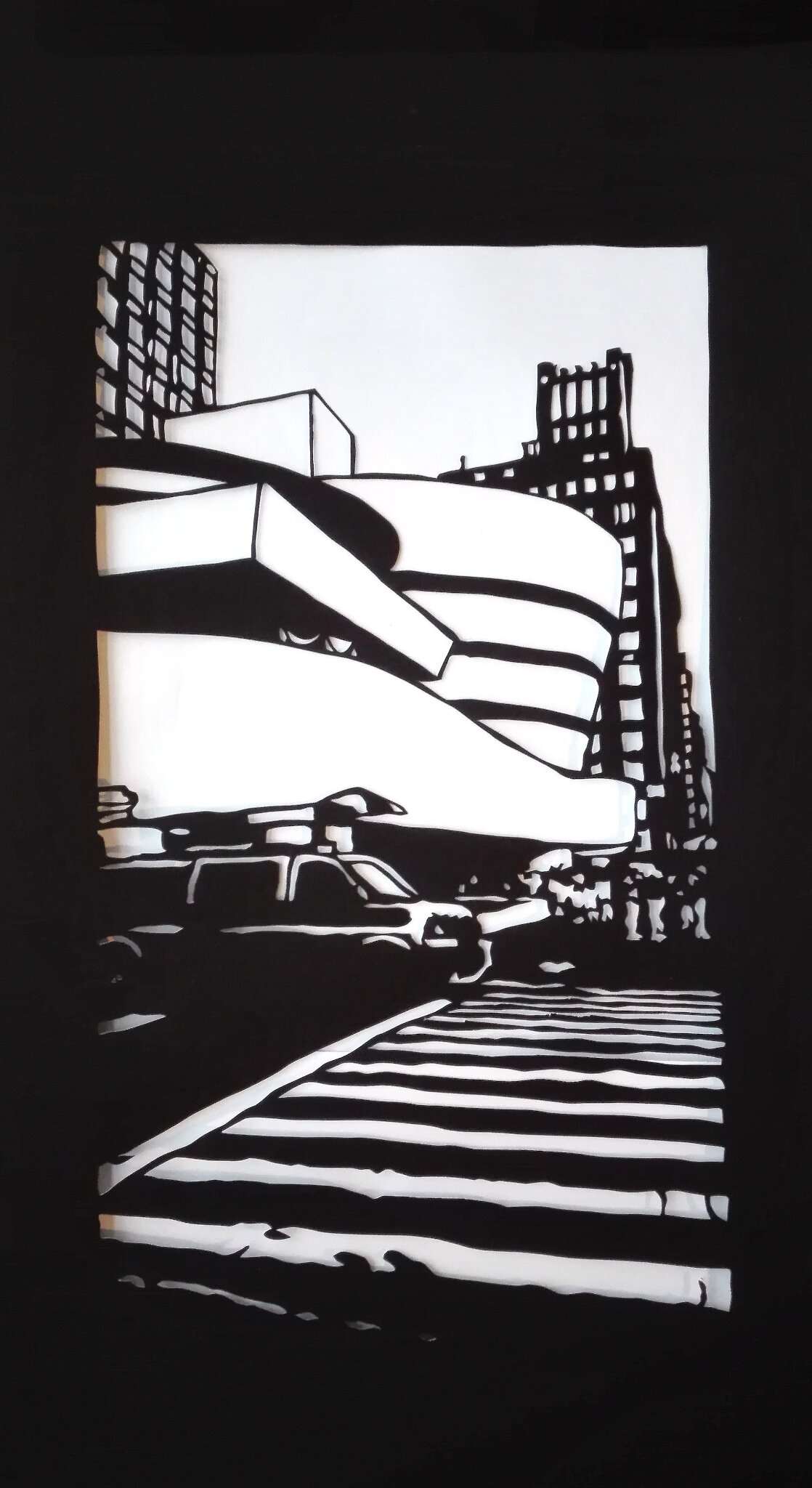 Black-and-white paper cut depicting a New York street scene with buildings, cars, and crosswalk.