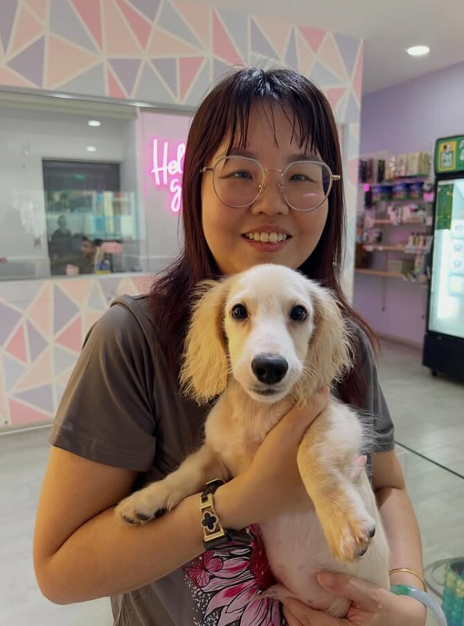 A woman holds a small dog in a pet store, embodying authenticity and connection in personal branding.