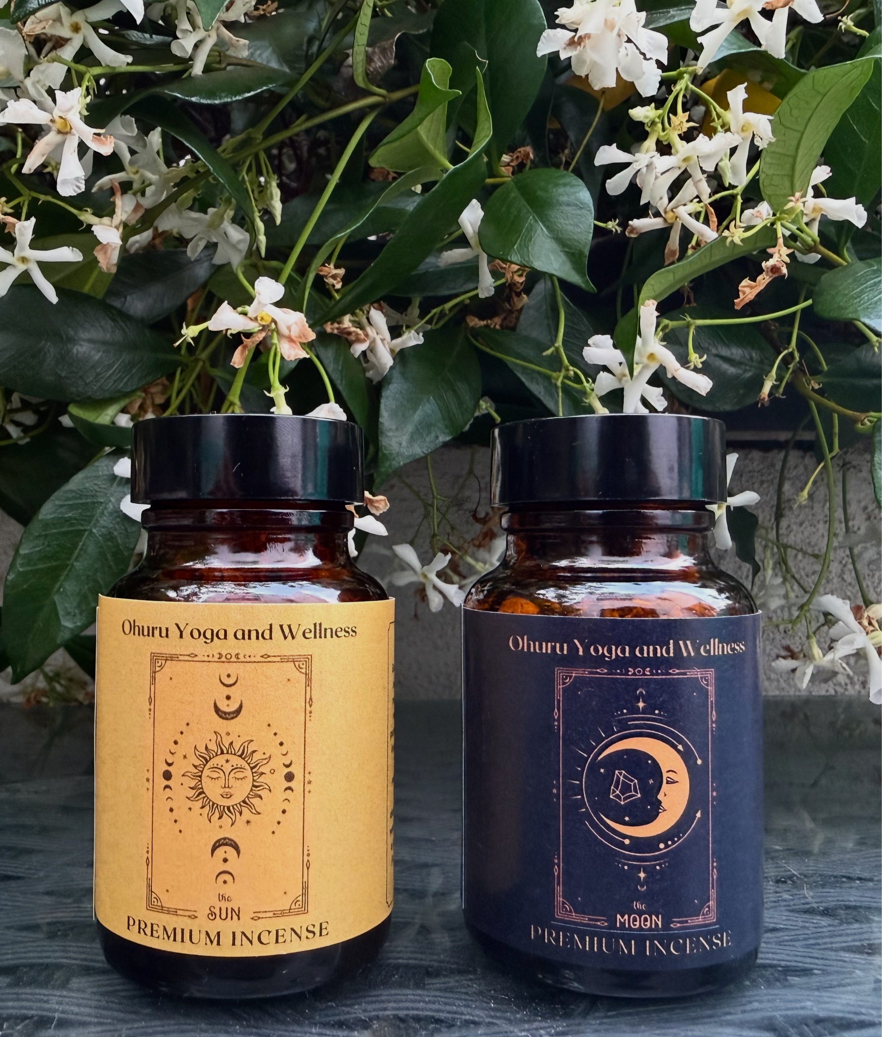 Ohuru Yoga and Wellness premium incense jars displayed among white flowering vines.