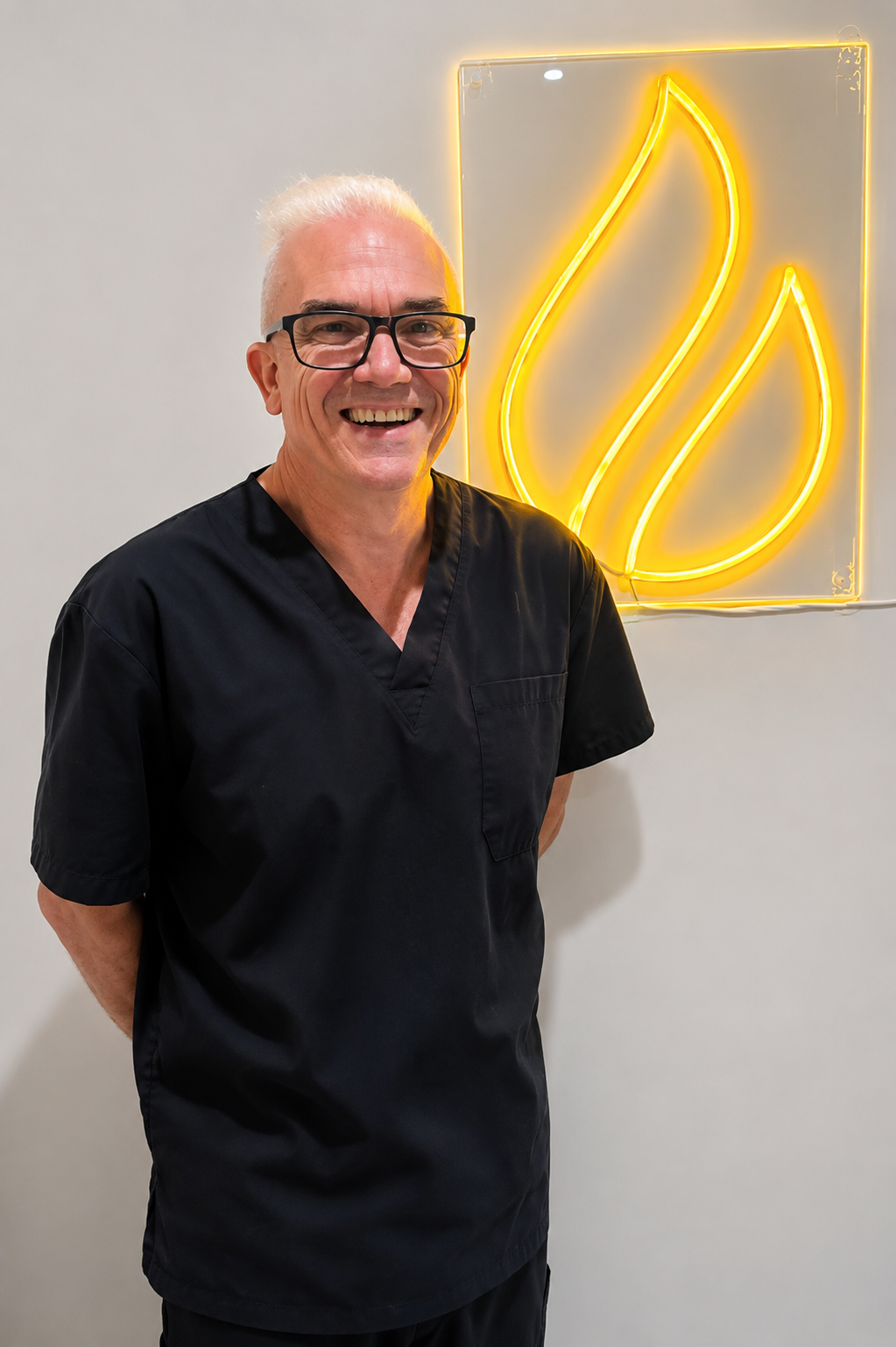 Corey Anderson RN smiling in clinic scrubs beside an illuminated Core Aesthetics logo.