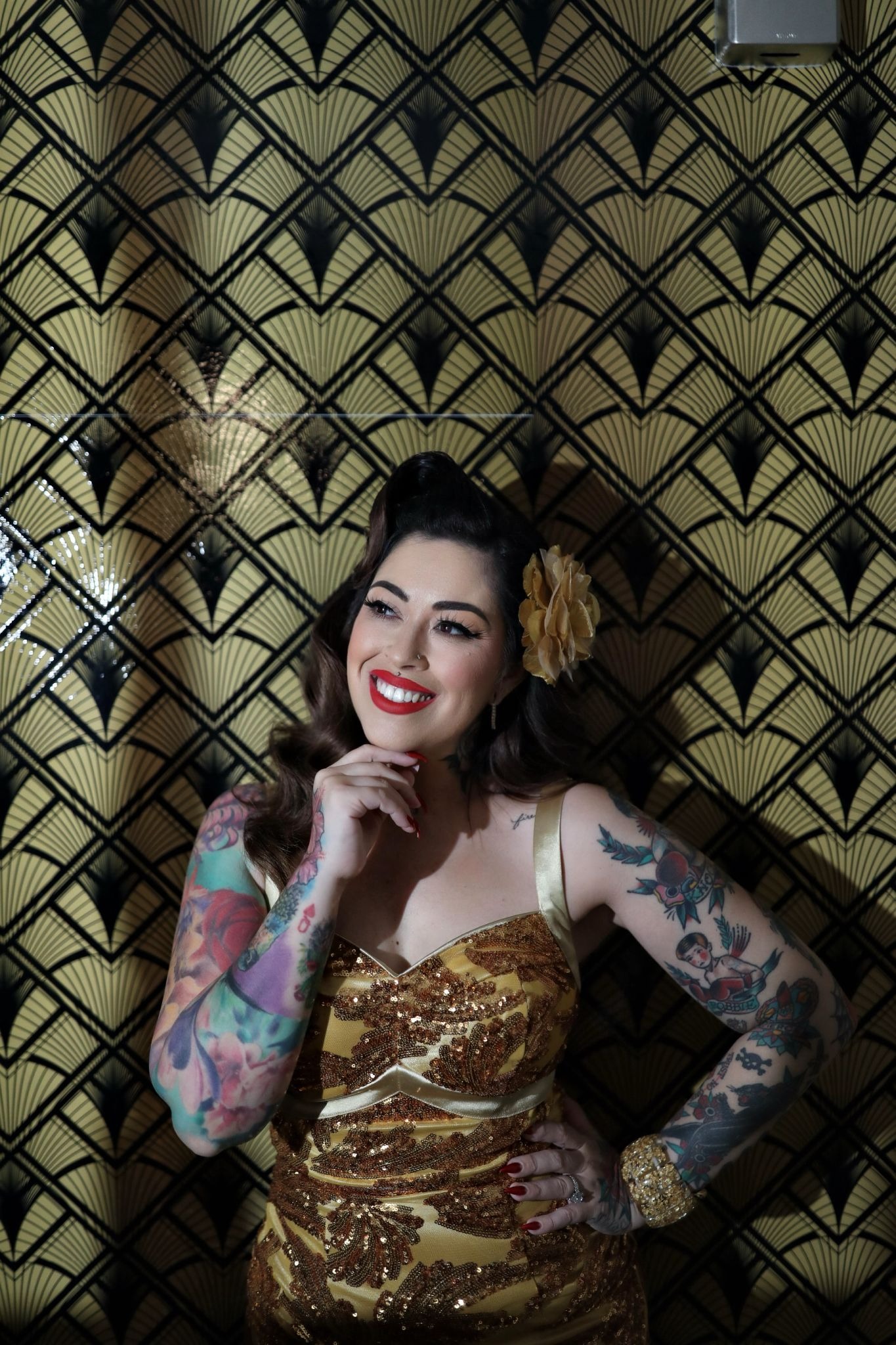 Priscila Swickard smiling in gold dress, showcasing tattoo artistry and beauty expertise at The Iconic Parlour.