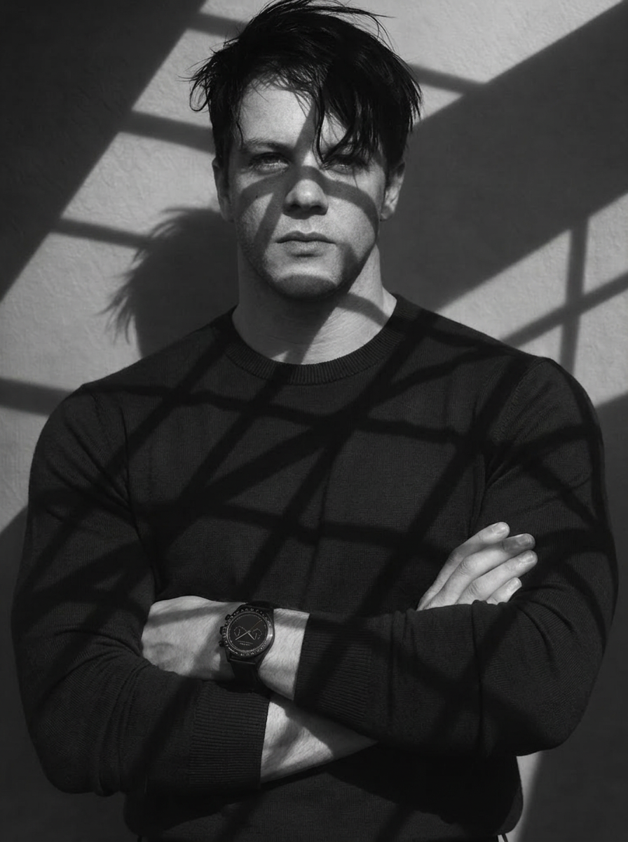 Man wearing a Mercier Prototype watch, standing with crossed arms in dramatic black-and-white lighting.