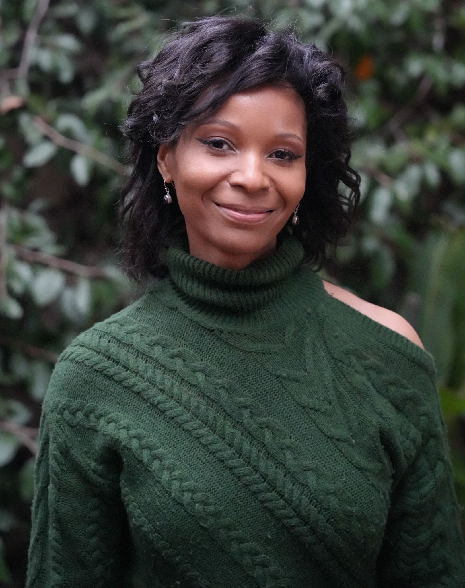 Founder Chidimma Iheonu smiling outdoors in a green knit sweater.