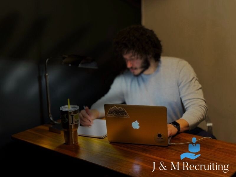 Marc Sambolin working at a laptop while taking notes at a desk.