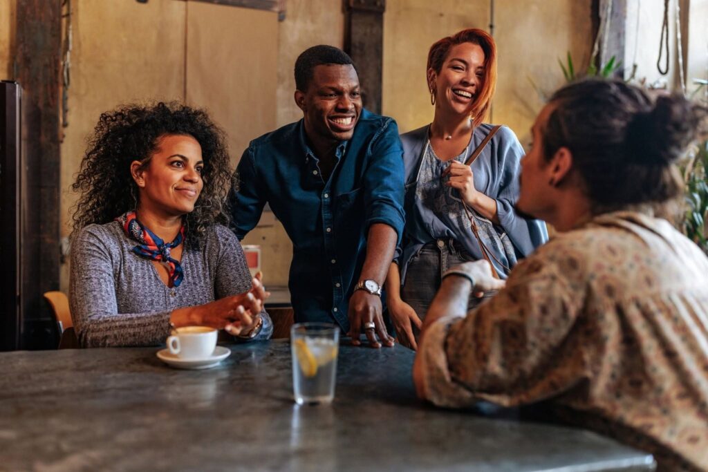 Group of friends chatting and laughing together at a café.