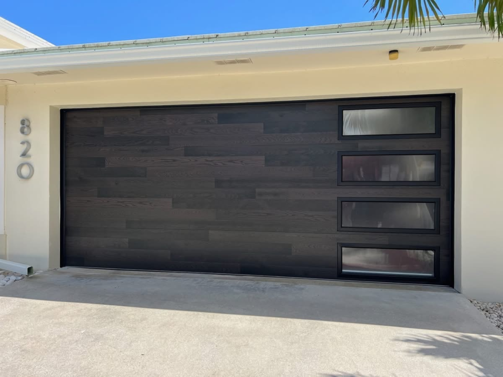 Modern black garage door with four horizontal windows on a residential home.