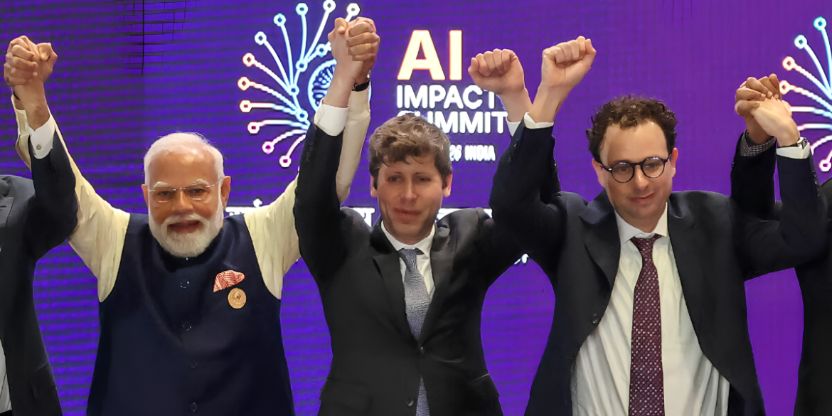 AI industry leaders raise joined hands onstage during an AI Impact Summit.